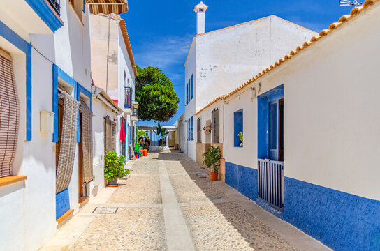 Typical old buildings traditional white-blue houses on pedestrian empty street Tabarca Island Nueva Tabarca Isla Plana village town in sunny summer day, Alicante province, Valencian Community, Spain