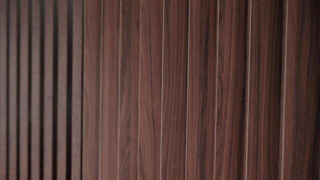 Elegant wooden slats of a decorative wall panel creating a dynamic background with a play of light and shadow, highlighting the natural wood grain texture for a modern interior design