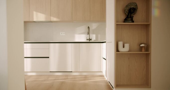 Modern kitchen interior with wooden cabinets and laminate flooring basking in the warm morning sunlight, showcasing a clean, minimalist design with elegant decorative elements on the shelves