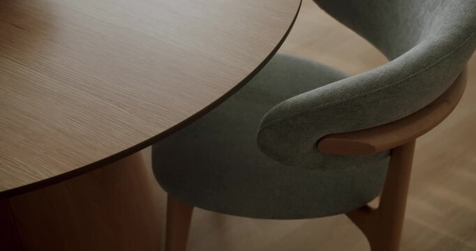 High-angle view showing an elegant modern dining room setting with a stylish gray upholstered chair next to a round wooden table. Highlighting contemporary interior design and furniture craftsmanship