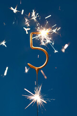 5 years celebration festive background with copy space made with Bengal fire in the form of number Five. Vertical photography.