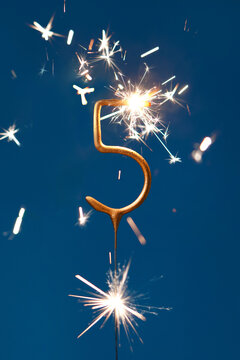 5 years celebration festive background with copy space made with Bengal fire in the form of number Five. Vertical photography.
