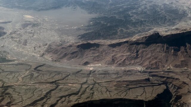 flying across landscape near Yanqul, a Wilayat of Ad Dhahirah Governorate in the Sultanate of Oman with desert, died riverbeds and mountain landscape all around  - 4k aerial video footage