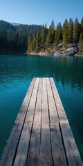 Fototapeta premium Weathered wooden pier extending into deep turquoise lake bordered by pine forest and rocky shore beneath distant mountain ridges