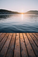 Fototapeta premium Closeup wooden dock planks with shimmering lake and soft sunrise light on distant hills