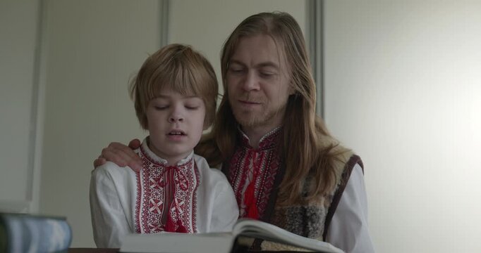 Man and Kid Boy Watch Family Album Together. Family in Ukrainian Traditional Attire Father Dad Son Relations Childhood. 4K 10-bit