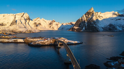 Scenic bridge over fjord with snow covered mountains in Lofoten Islands, Norway at golden hour