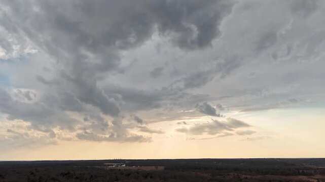 Aerial drone hyperlapse of storm clouds clearing as sunlight breaks through the sky over rural Oklahoma landscape after a thunderstorm.