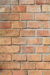 Obraz premium A clean vertical shot of a classic red brick wall featuring various shades of clay and rough surface textures with grey mortar.