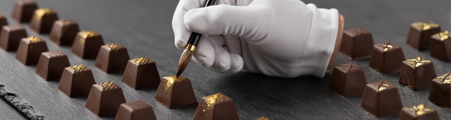 Pastry chef decorating chocolates on slate serving board