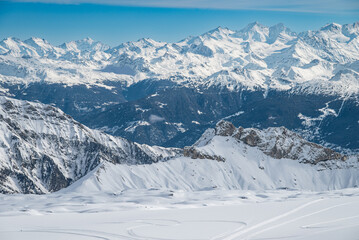 Fototapeta premium Panoramic view of snowy mountain range under clear blue sky