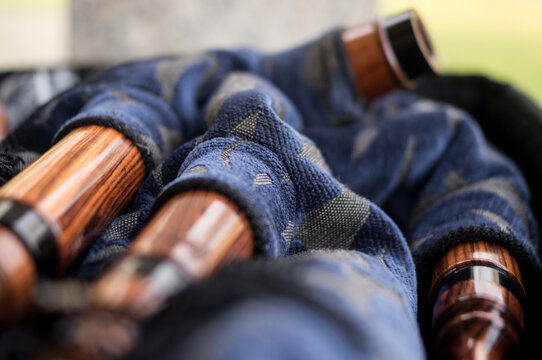 A macro shot focusing on the polished wood grain and craftsmanship of bagpipe pipes resting on a blue patterned bag
