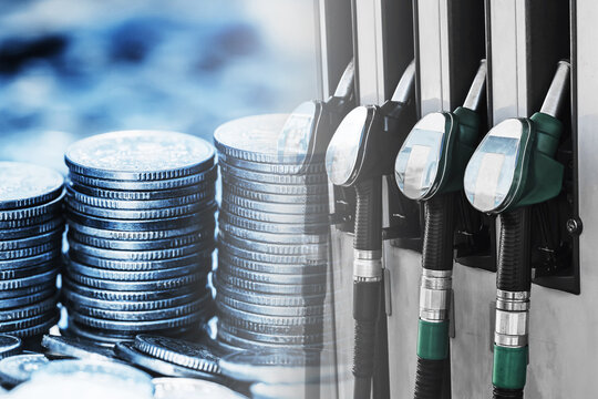 Fuel prices and transportation costs concept. Petrol pump nozzles next to stacks of coins showing gasoline expenses and energy economy. Rising fuel cost and financial impact on mobility and transport
