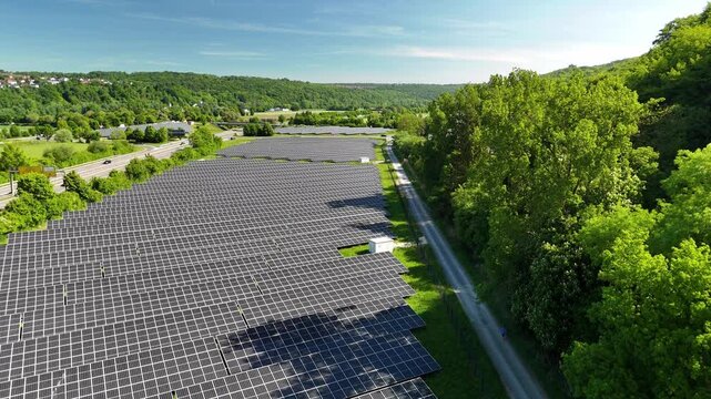 Aerial drone footage of ascent over photovoltaic solar panels next to a highway in summer