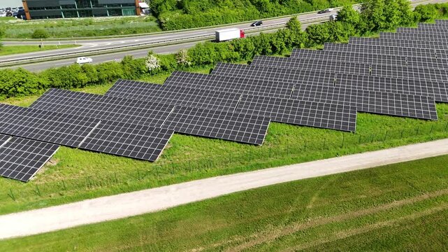 Aerial drone footage of orbiting over photovoltaic solar panels next to a freeway in summer