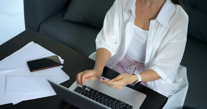 Lady using laptop calmly during day. Woman concentrating on computer in cozy workspace environment. Female individual engaged in productive computer work in relaxed home setting with documents