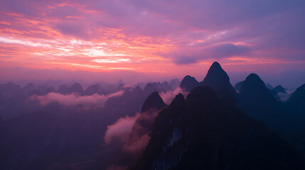 Naklejka premium Dramatic landscape of mountain peaks at sunrise with vibrant pink and purple sky, showcasing a beautiful, ethereal natural phenomenon