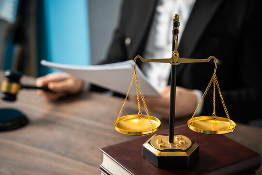 Judge holding a verdict in one hand and a gavel in the other, with scales in view, symbolizing justice, authority, and legal decision-making.