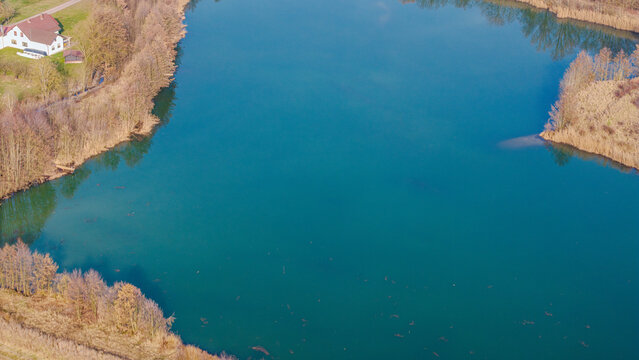 Ein Blick auf den klaren See neben einem kleinen Geh&ouml;ft in einer l&auml;ndlichen Gegend im Fr&uuml;hling