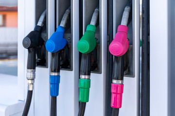 Colorful Fuel Nozzles at Gas Station Pump. Close-up of black, blue, green, and pink fuel nozzles lined up at a gas station pump, showing energy, transport, and refueling. © Iryna