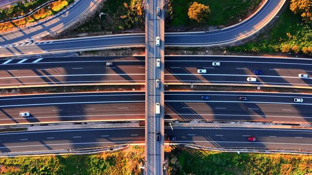 Multi-lane motorway with a bridge crossing overhead and vehicles in motion. Top down arial view of highway lanes and overpass.