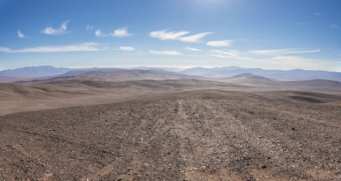 Panoramic view of Atacama Desert, Vaca Muerta strewnfield, Chile. Vast arid landscape with rocky terrain and distant mountains under a clear blue sky in the Atacama Desert, Chile.
