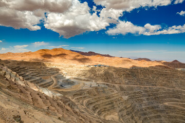 A vast open pit copper mine features deep terraces carved into the desert landscape of northern...