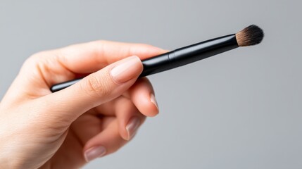 Woman's Hand Holding Sleek Makeup Brush with Soft Bristles for Beauty Routine