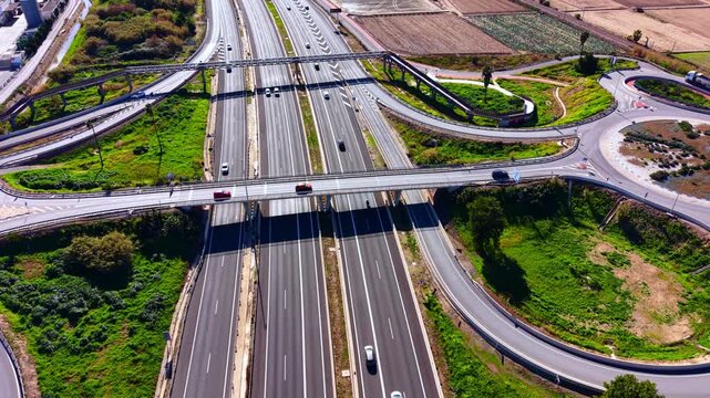 Complex highway system with cars, asphalt roads, green grass, and bridges in Spain. Aerial view of a multi level highway interchange junction.