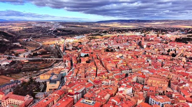 Dense historic city center with narrow streets, towers and uniform red tiled rooftops. High angle aerial view of Spanish old downtown.