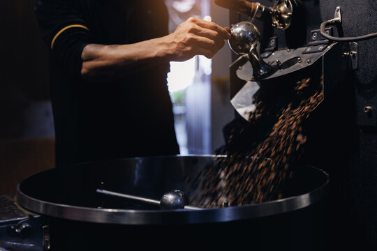 Coffee roaster operator pouring beans into cooling drum