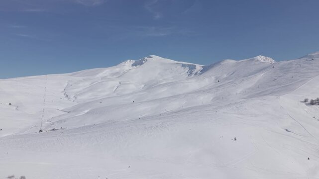 Aerial panning right shot sweeping across the majestic snow-capped mountain peak of Uludag