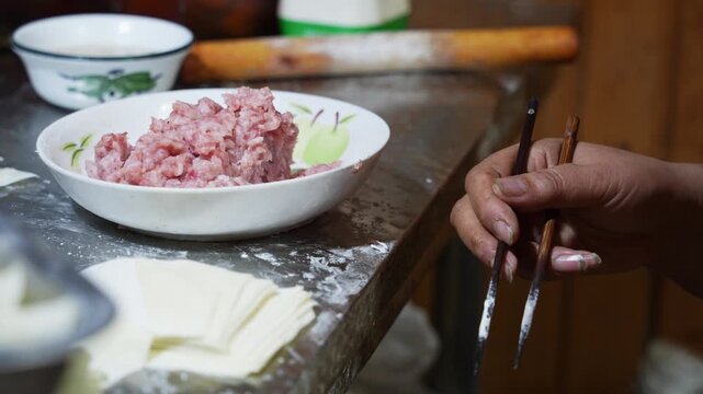 Handmade dumpling preparation with minced meat filling and dough wrappers on a kitchen counter