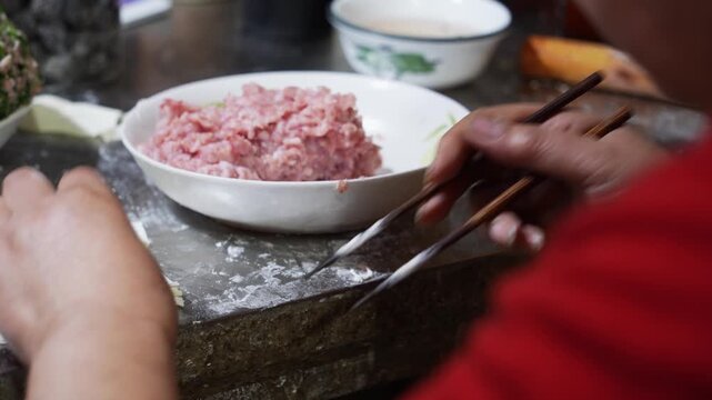 Handmade dumpling preparation with minced pork filling and dough wrappers on a stone countertop