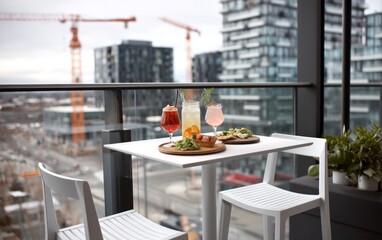 Fototapeta premium Relaxing Outdoor Dining Setup with Drinks and Snacks on a Modern Balcony