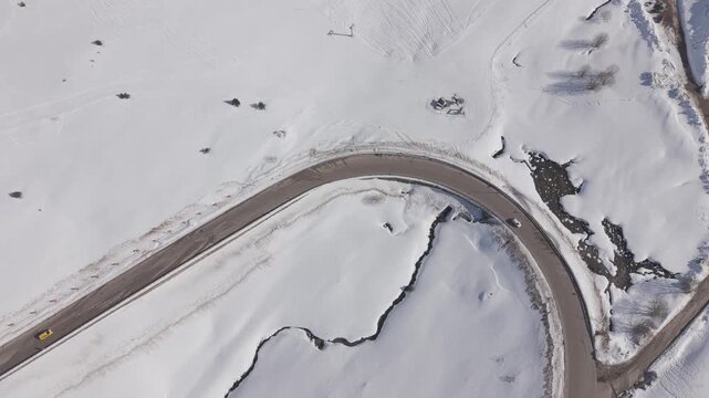 Aerial forward tracking shot over a snow-covered ski resort and mountain road at Uludag