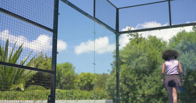 Player is bending to pick ball, tossing and serving overhead with perforated paddle on blue court