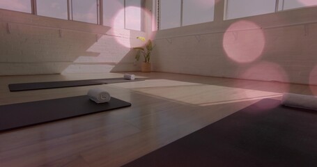 Lining three black yoga mats with rolled white towels at studio windows, sunlight casting lines