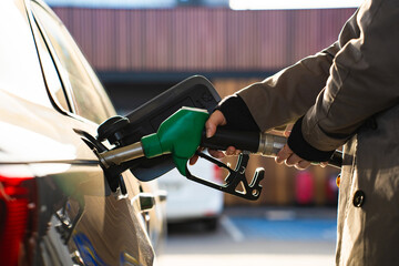 Hand holding gasoline nozzle while refilling vehicle tank © Rabizo Anatolii