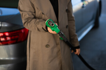 Hand holding gasoline nozzle at fuel station close-up. Driver refueling car using gasoline pump © Rabizo Anatolii