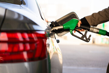 Close-up of hand refilling vehicle with gasoline. Fuel pump inserted into tank during refueling © Rabizo Anatolii