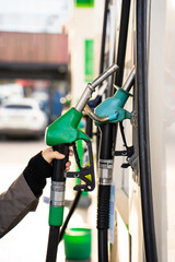 Hand holding gasoline nozzle at fuel station close-up. Driver refueling car using gasoline pump © Rabizo Anatolii