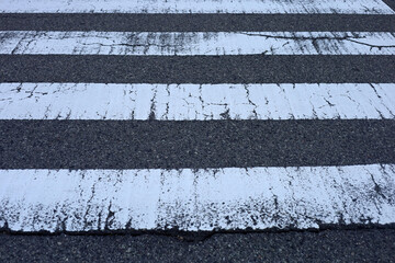 Worn pedestrian crosswalk lines on asphalt road © Bowonpat