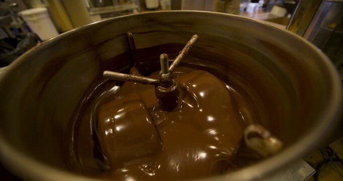 Melted chocolate spinning in large container - closeup
