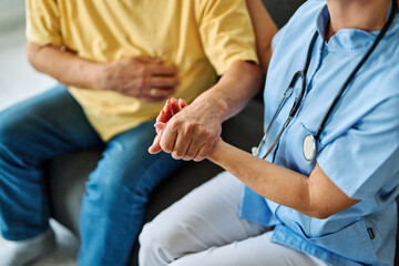 Fototapeta premium Doctor or nurse caregiver's hand giving support to sad lonely senior man at home or nursing home