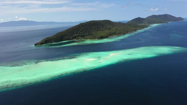 Aerial circling view of Mansuar and Kri islands revealing turquoise coral reef and atoll formations Raja Ampat