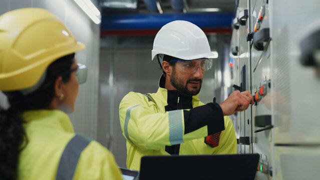 Technician and electrician use computer and tablet diagnostics to analyze control panels, optimize energy use and prevent downtime. 