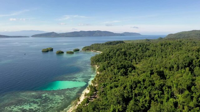 Aerial flight over dense tropical forest and coral coastline with Fam Islands in the distance Raja Ampat