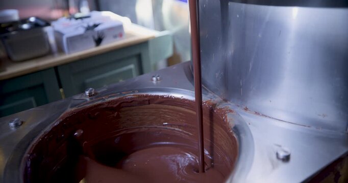 Steady cam movement up and down as chocolate is poured and stirred in machine