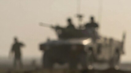 Military armored vehicle with soldiers on patrol in a dusty heat haze environment, conveying conflict and defense concepts